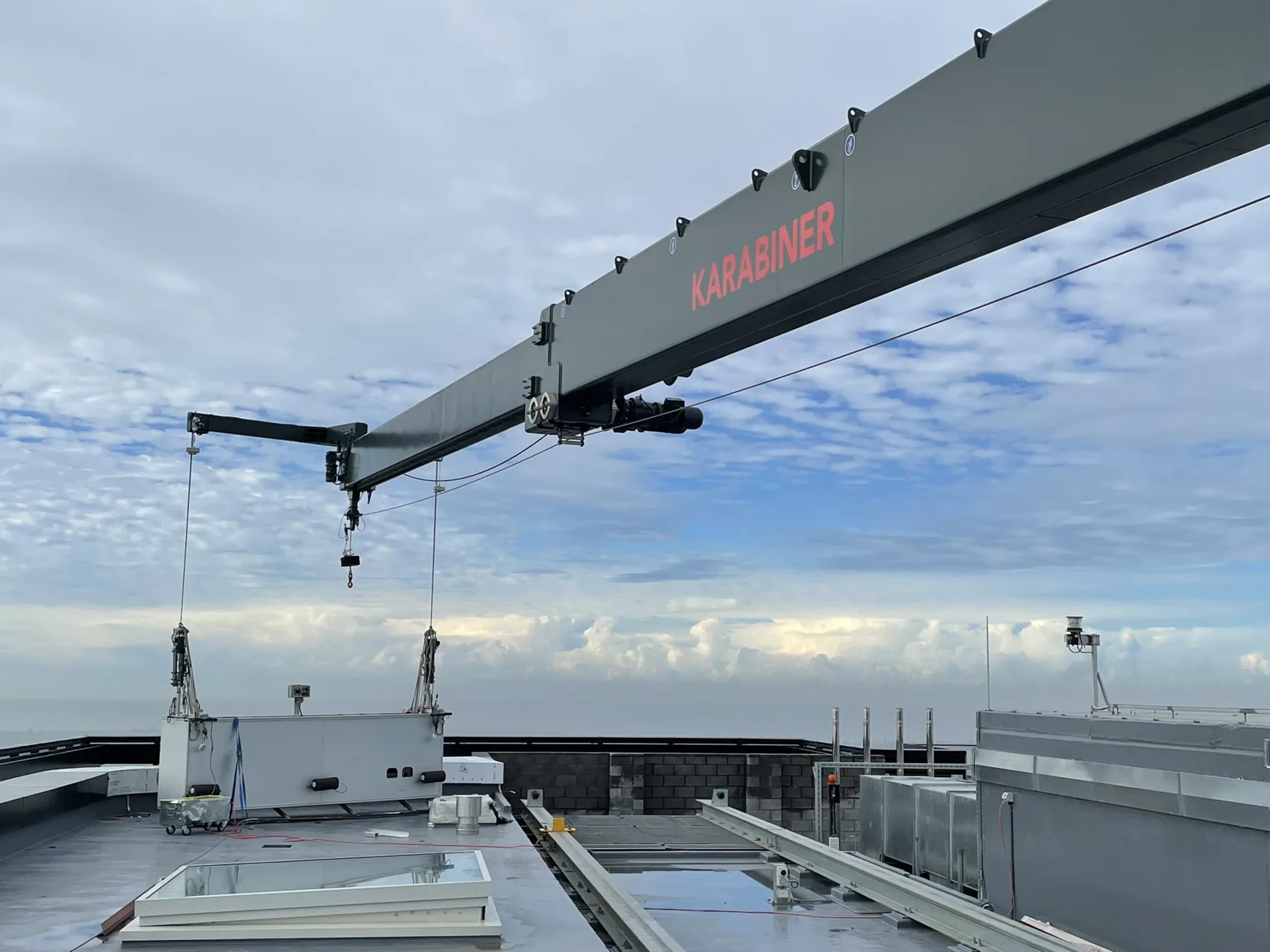 Karabiner BMU jib extended over a rooftop with the cradle suspended below