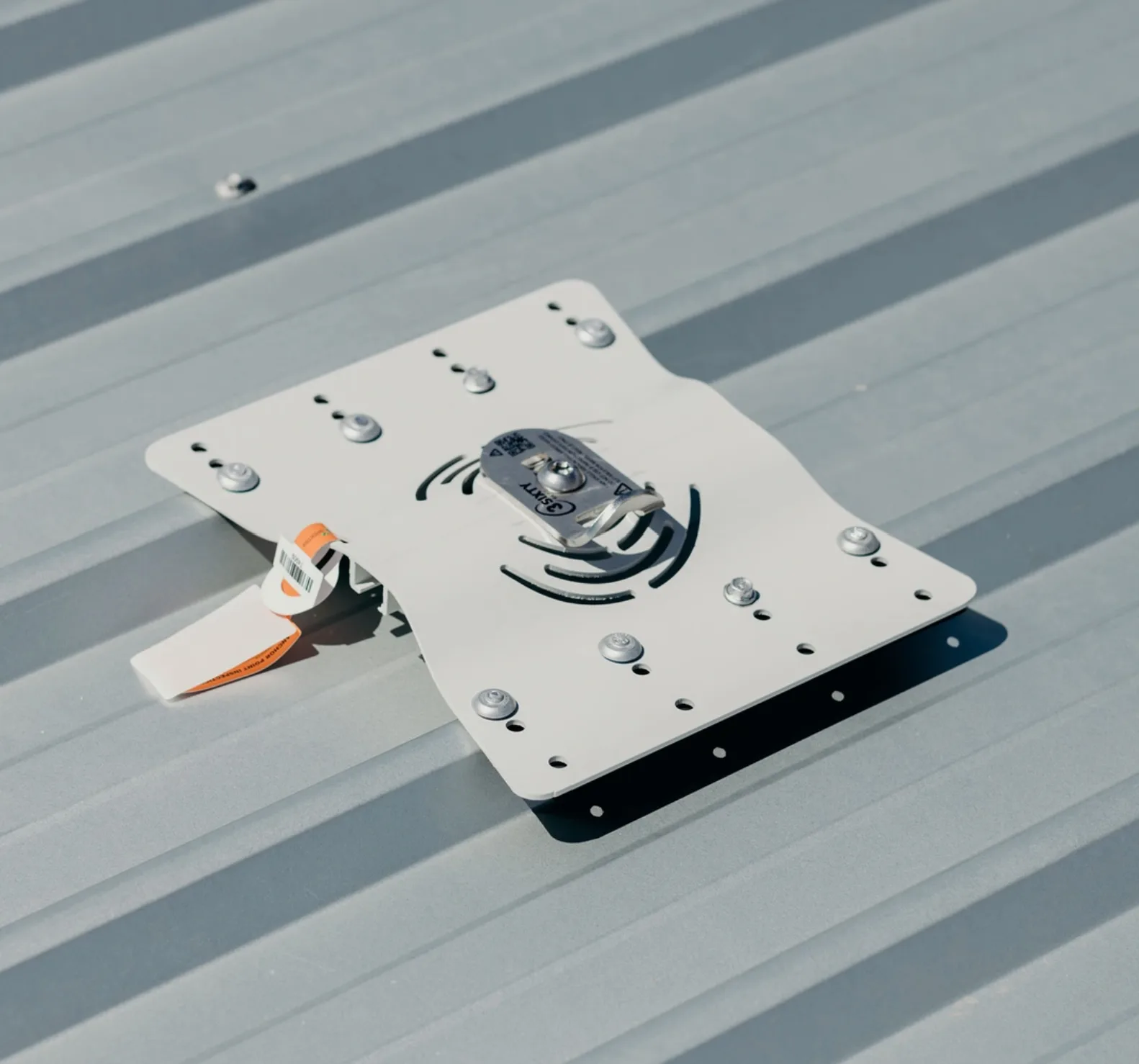 Roof anchor plate fixed to a metal roof, with its inspection tag attached